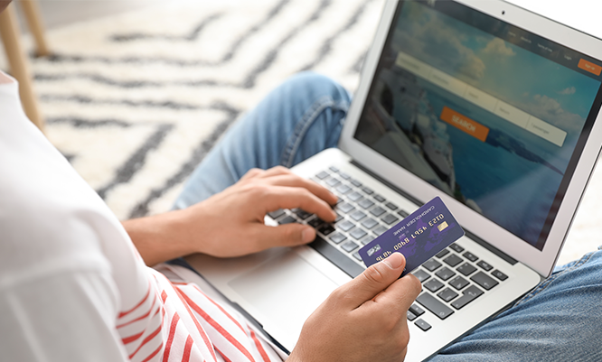 Person bucht mit Laptop und Kreditkarte Flugtickets