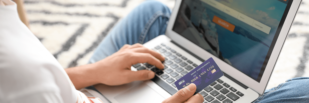 Mensch bucht Flug mit Kreditkarte am Laptop